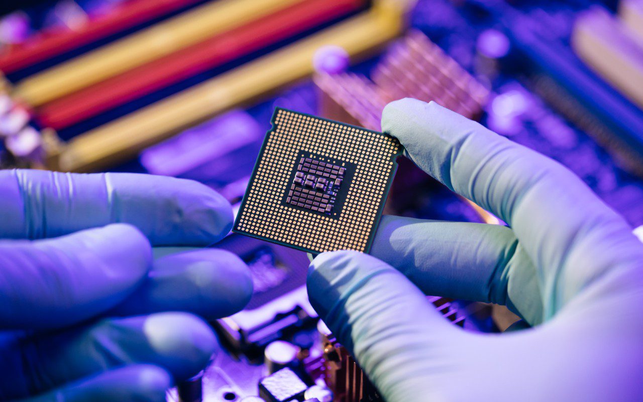 GettyImages-1296135852 Gloved hands holding a computer microchip.